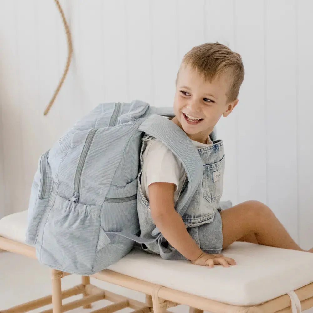 Personalised toddler backpack in corduroy – blue color. Child wearing custom name daycare backpack