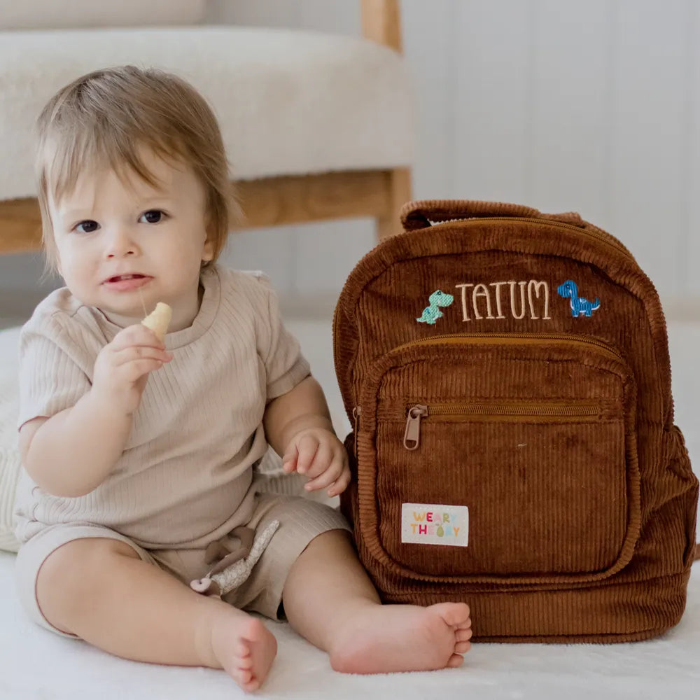 Personalised toddler backpack in corduroy – brown color. Child wearing custom name daycare backpack