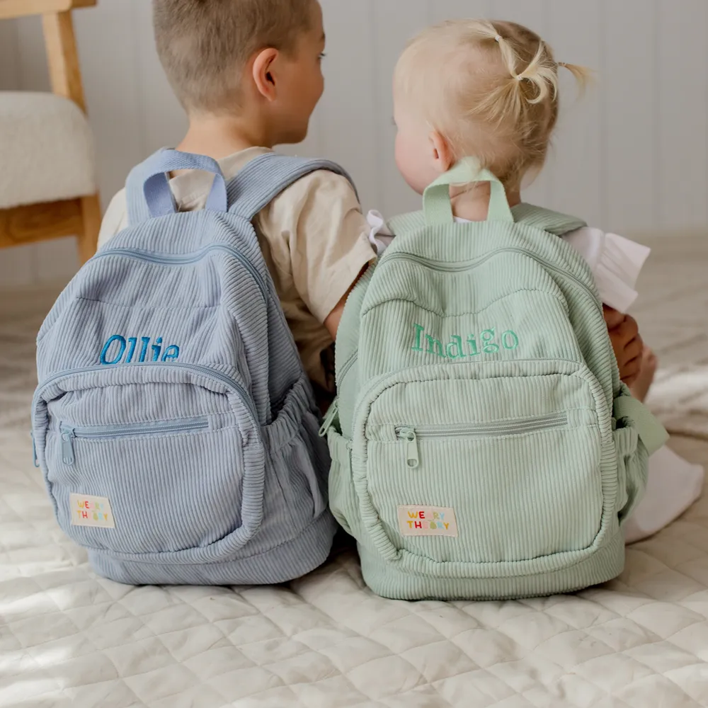 Two children wearing the Blueberry Corduroy Backpack