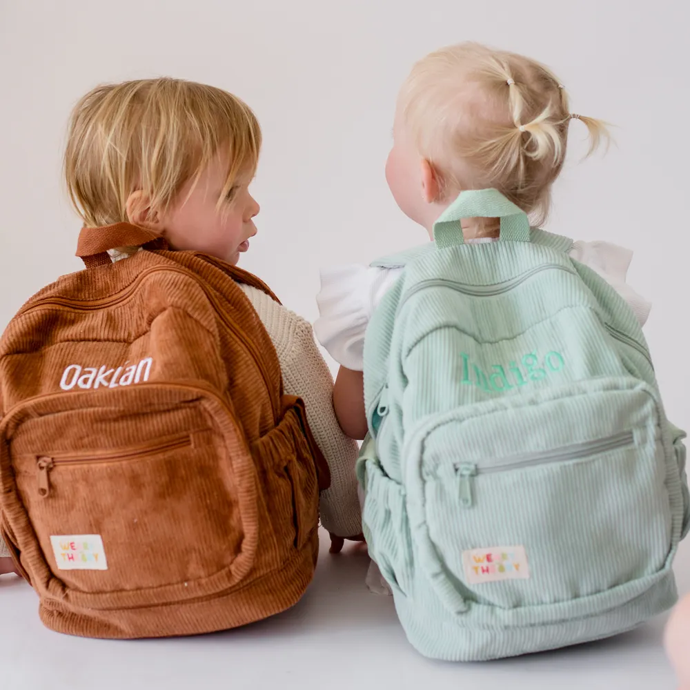 Two children wearing the Chocolate Corduroy Backpack