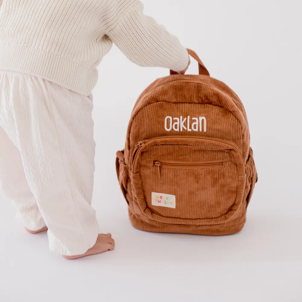 Child holding the Chocolate Corduroy Backpack