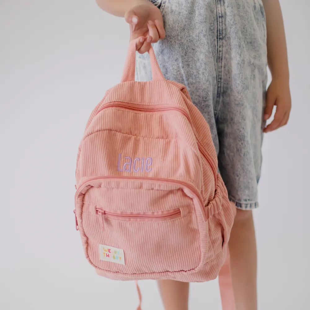 Child holding the Strawberry Corduroy Backpack