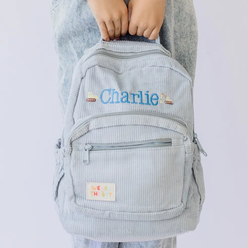 Personalised toddler backpack in corduroy – blue color. Child wearing custom name daycare backpack