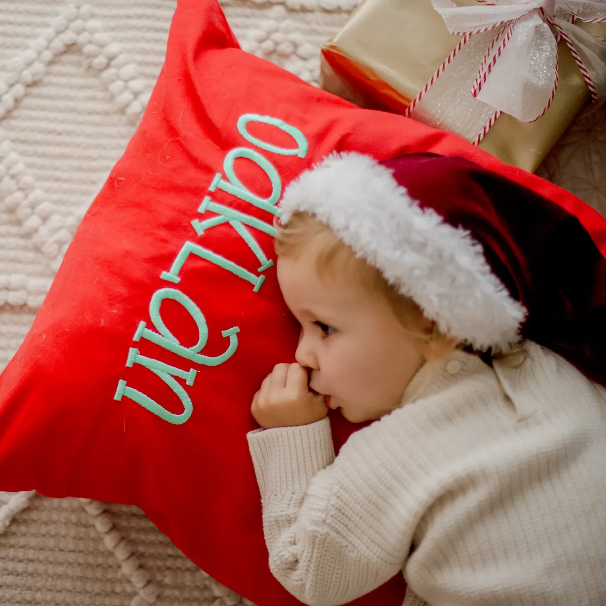 Red Santa sack with embroidered name used as a pillow